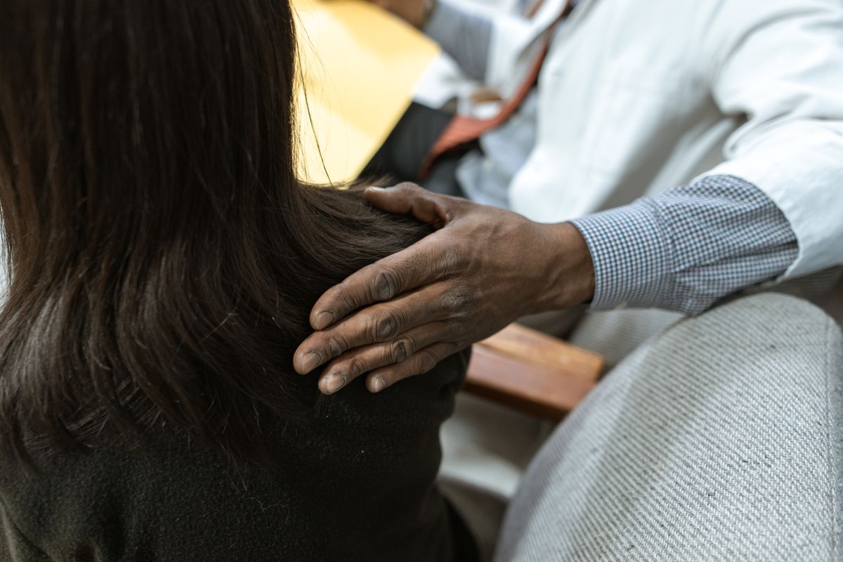 A reassuring hand resting on a colleague's shoulder in a supportive gesture