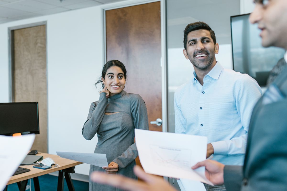 A young woman reviewing printed policy documents with two colleagues in a bright office