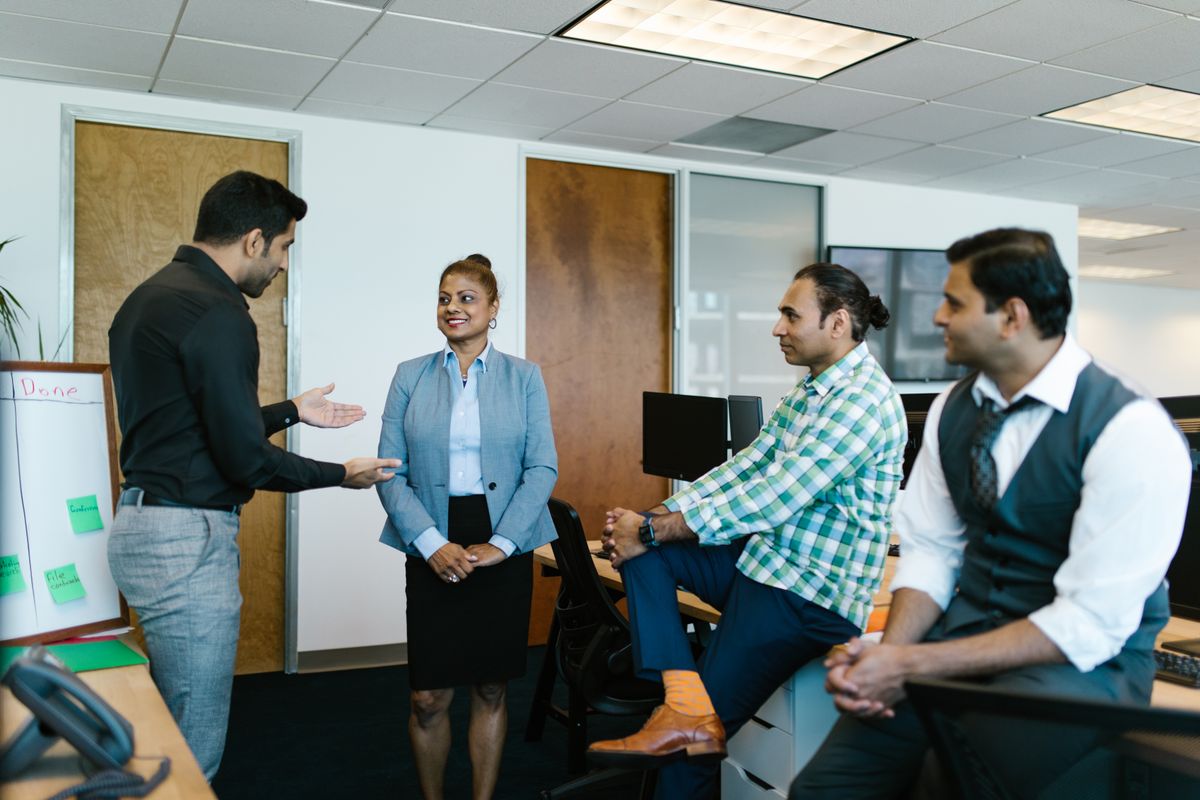 Four colleagues having a discussion during a workshop session in a bright office