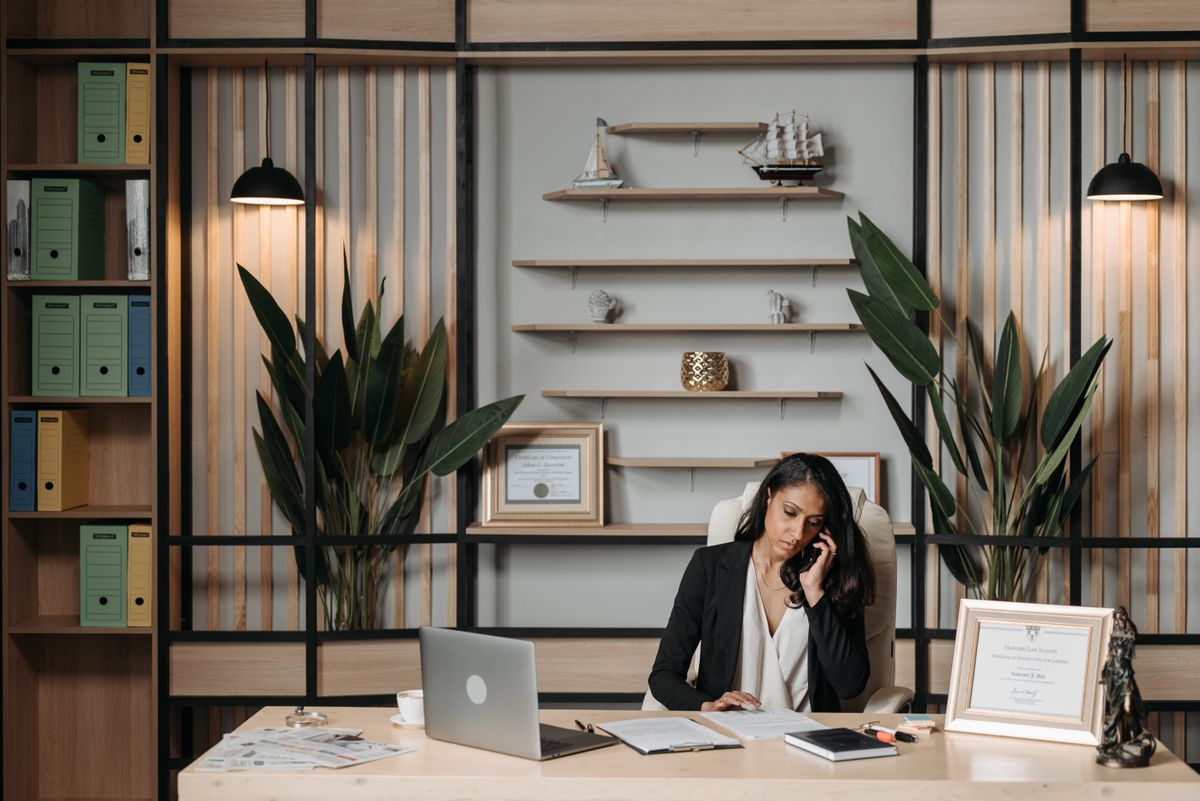 A young woman on a phone call at her desk in a bright office, attentive and focused